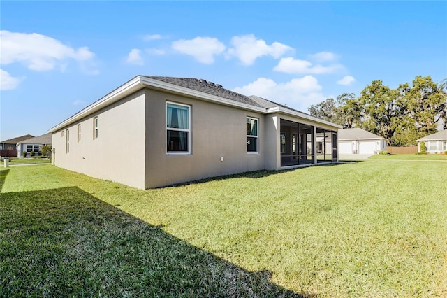 back of property featuring a sunroom, a yard, and a garage