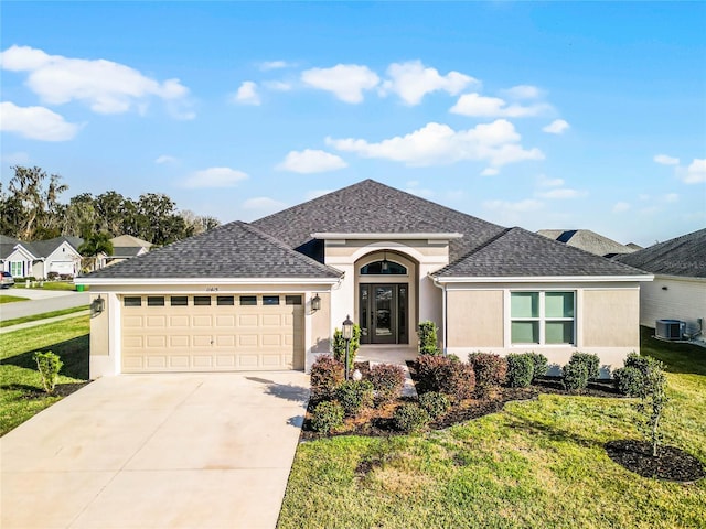 single story home with a front yard, a garage, and central air condition unit