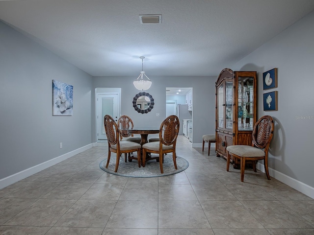 tiled dining room featuring a textured ceiling