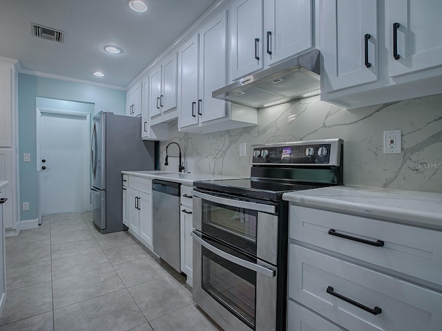 kitchen with backsplash, ornamental molding, light tile patterned flooring, white cabinetry, and stainless steel appliances