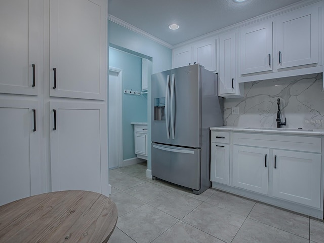 kitchen with white cabinetry, sink, tasteful backsplash, stainless steel fridge, and crown molding