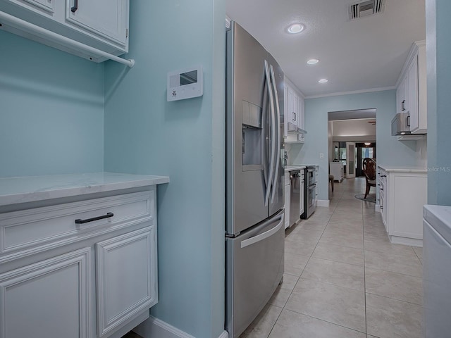 kitchen with white cabinets, light stone counters, appliances with stainless steel finishes, light tile patterned flooring, and ornamental molding