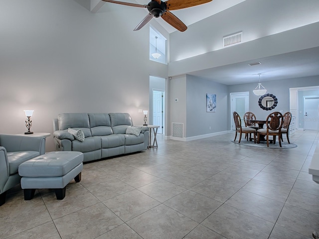 tiled living room featuring ceiling fan and a high ceiling