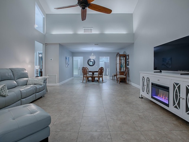 living room featuring ceiling fan, light tile patterned floors, and a high ceiling