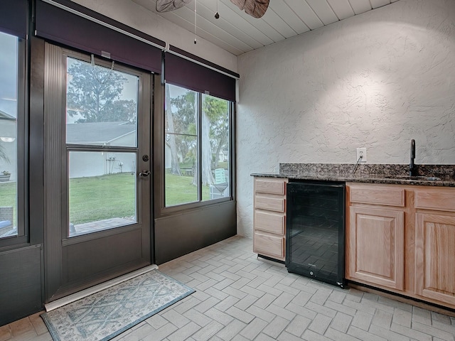 doorway to outside with a wealth of natural light, ceiling fan, beverage cooler, and indoor wet bar