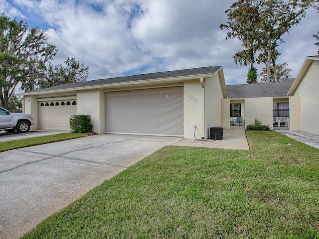 view of side of home featuring a garage, a lawn, driveway, and stucco siding