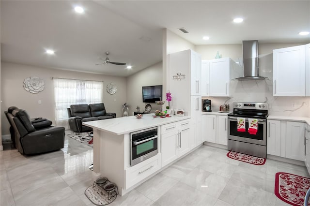 kitchen featuring kitchen peninsula, stainless steel appliances, white cabinetry, and wall chimney exhaust hood