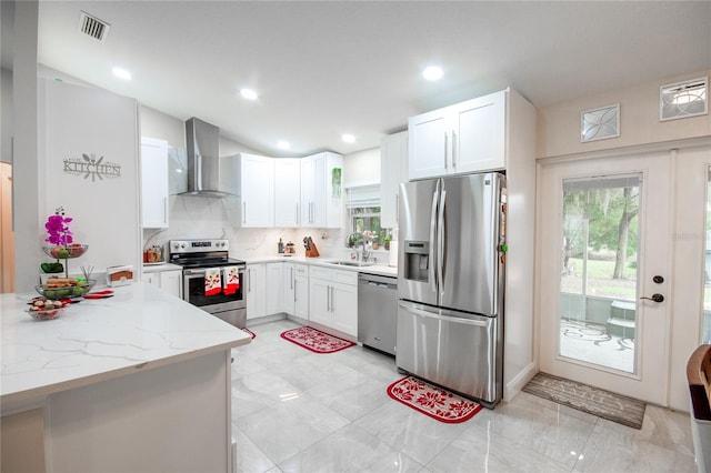 kitchen featuring white cabinets, light stone countertops, wall chimney range hood, and stainless steel appliances