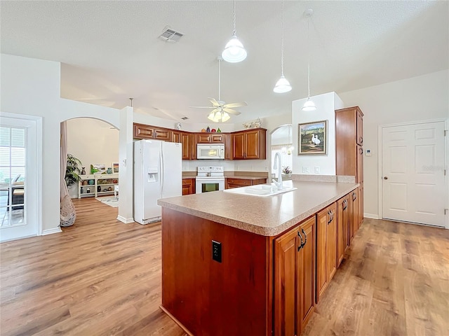 kitchen featuring kitchen peninsula, light wood-type flooring, white appliances, and hanging light fixtures