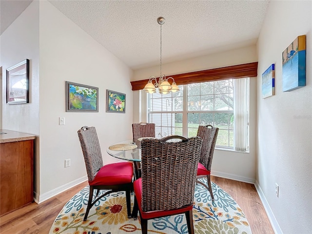 dining room with a chandelier, a textured ceiling, and light hardwood / wood-style flooring