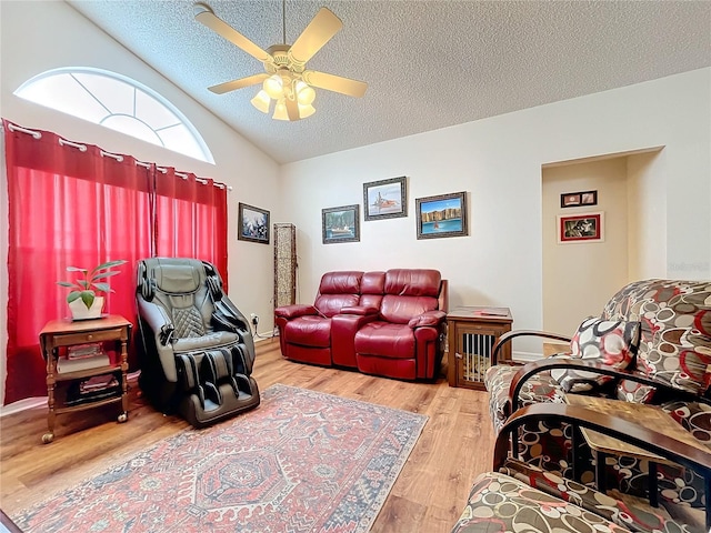 living room with vaulted ceiling, ceiling fan, light hardwood / wood-style floors, and a textured ceiling