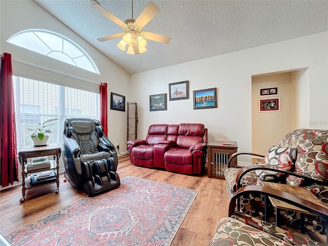 living room featuring a textured ceiling, light hardwood / wood-style floors, ceiling fan, and lofted ceiling