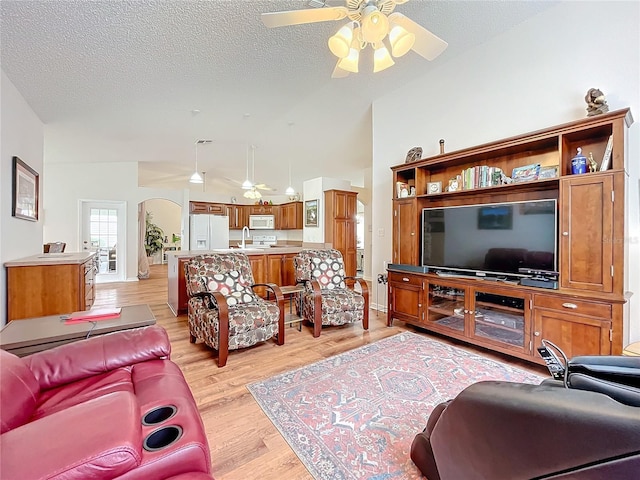 living room with ceiling fan, light hardwood / wood-style flooring, a textured ceiling, and sink