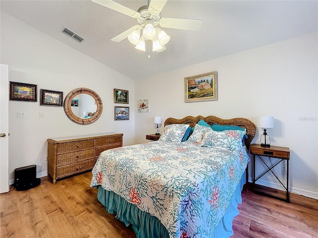 bedroom with a textured ceiling, ceiling fan, lofted ceiling, and hardwood / wood-style flooring