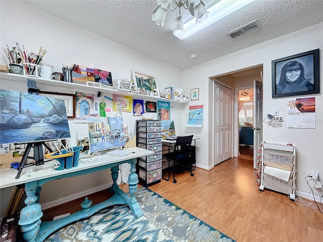 home office featuring hardwood / wood-style floors, ceiling fan, a textured ceiling, and heating unit