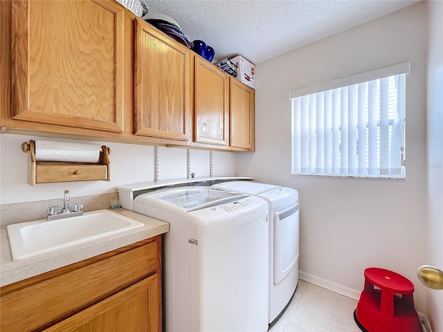 washroom featuring washer and dryer, sink, cabinets, and a textured ceiling