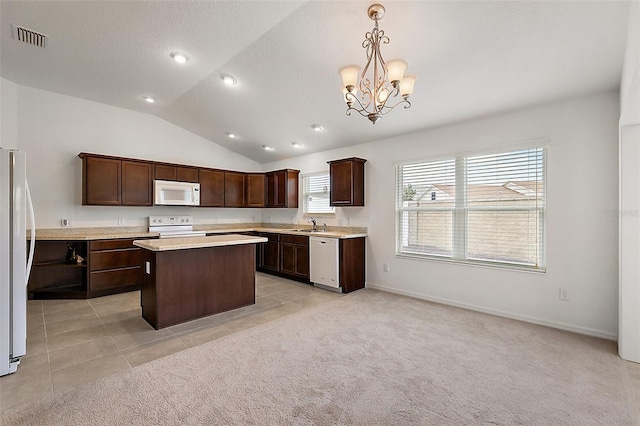 kitchen with white appliances, dark brown cabinetry, a kitchen island, hanging light fixtures, and vaulted ceiling