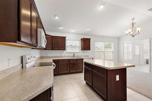 kitchen with white appliances, lofted ceiling, a chandelier, a kitchen island, and pendant lighting