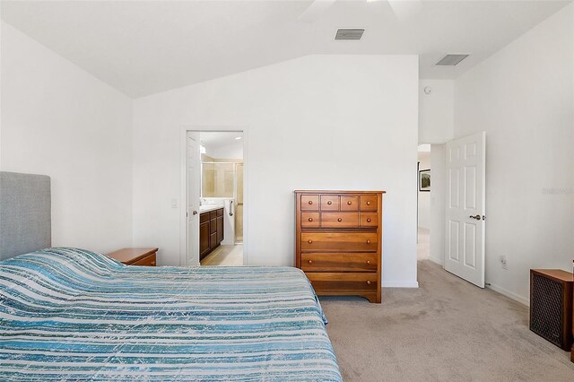 bedroom featuring ceiling fan, ensuite bath, light colored carpet, and lofted ceiling