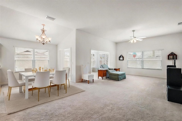 carpeted dining area featuring plenty of natural light and ceiling fan with notable chandelier