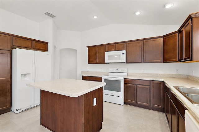 kitchen featuring white appliances, vaulted ceiling, a kitchen island, sink, and light tile patterned flooring