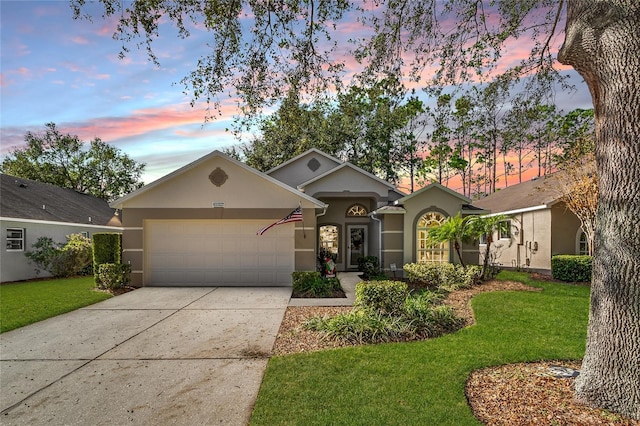 ranch-style home with a garage and a lawn