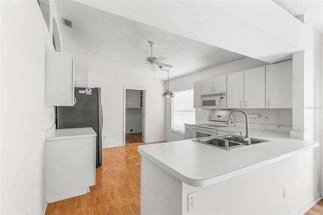 kitchen with sink, white appliances, ceiling fan, kitchen peninsula, and light wood-type flooring