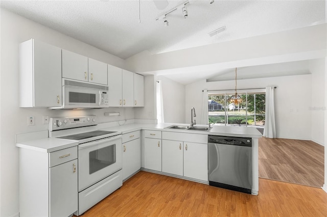 kitchen with sink, white appliances, white cabinetry, decorative light fixtures, and vaulted ceiling