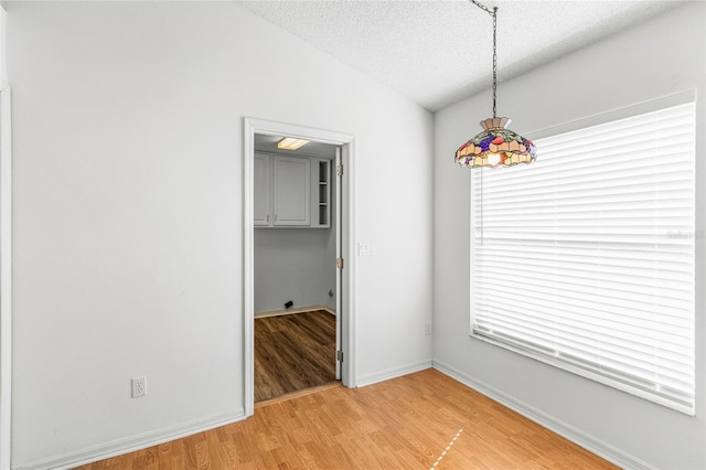 unfurnished room featuring lofted ceiling, hardwood / wood-style floors, and a textured ceiling