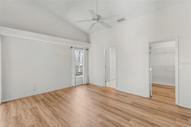 unfurnished bedroom with vaulted ceiling, a spacious closet, ceiling fan, and light wood-type flooring