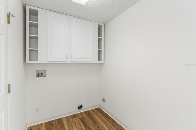 clothes washing area featuring washer hookup, dark wood-type flooring, cabinets, and a textured ceiling