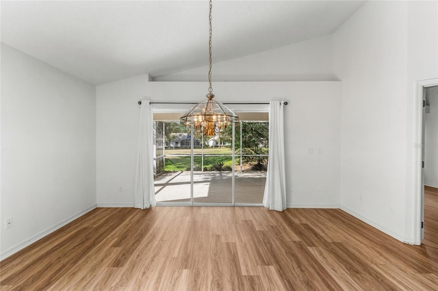 unfurnished dining area featuring lofted ceiling, wood-type flooring, and a chandelier