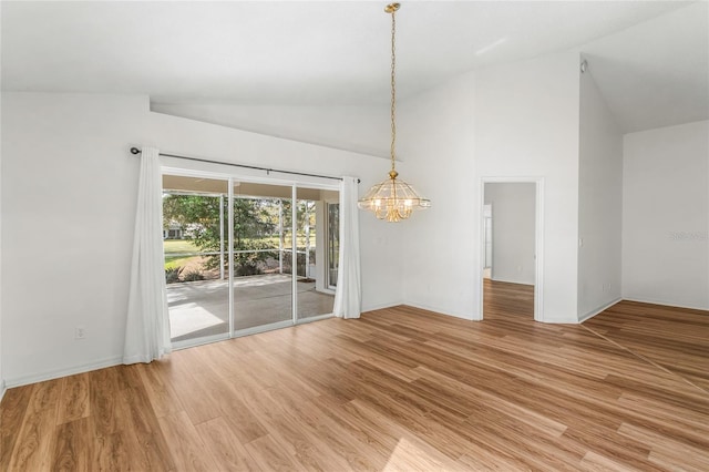 empty room featuring hardwood / wood-style flooring, high vaulted ceiling, and a notable chandelier