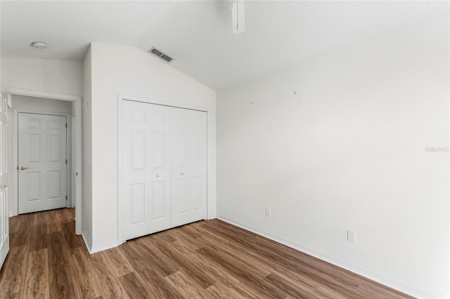 unfurnished bedroom featuring hardwood / wood-style floors, vaulted ceiling, and a closet