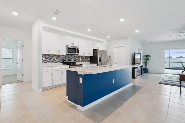 kitchen featuring stainless steel appliances, white cabinetry, a kitchen island with sink, and ceiling fan