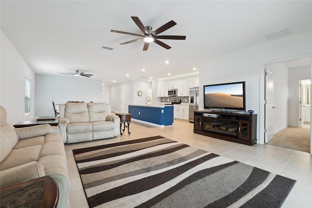 tiled living room featuring ceiling fan and sink