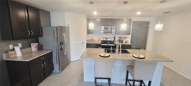 kitchen with decorative light fixtures, an island with sink, stainless steel appliances, and sink