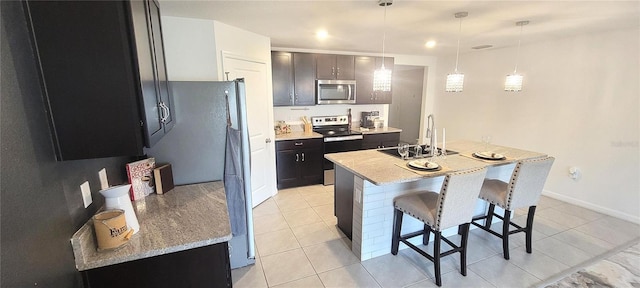 kitchen with sink, stainless steel appliances, hanging light fixtures, light stone counters, and light tile patterned floors