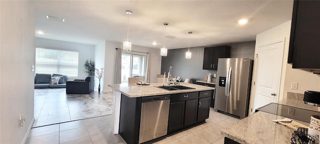 kitchen featuring decorative light fixtures, sink, stainless steel appliances, and a kitchen island with sink