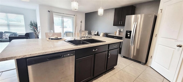 kitchen with appliances with stainless steel finishes, a wealth of natural light, sink, decorative light fixtures, and an island with sink