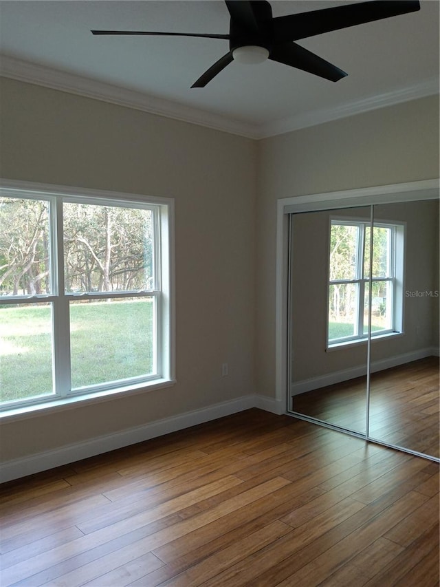 unfurnished bedroom featuring ceiling fan, multiple windows, a closet, and crown molding