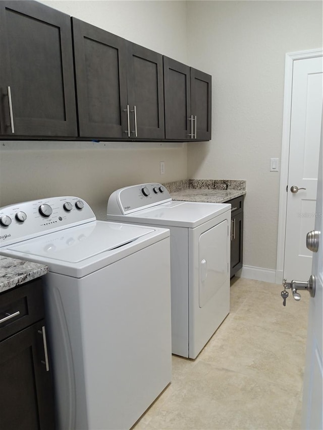 clothes washing area featuring washing machine and dryer and cabinets