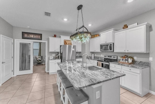 kitchen featuring light stone countertops, appliances with stainless steel finishes, sink, a center island with sink, and white cabinetry