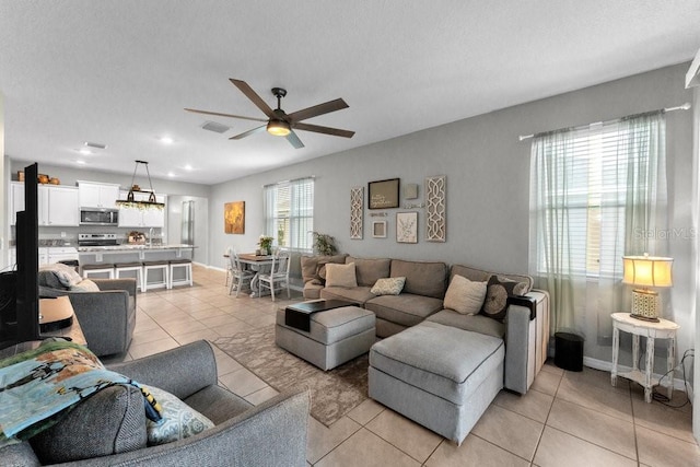 living room featuring ceiling fan, light tile patterned flooring, and a textured ceiling