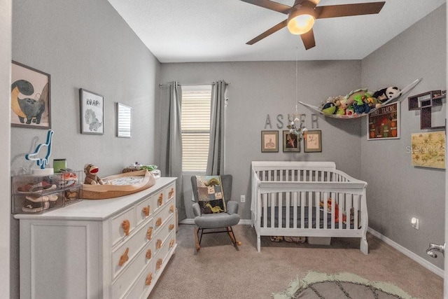 bedroom with ceiling fan, a crib, and light carpet