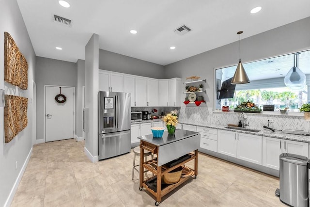 kitchen with light stone countertops, stainless steel fridge with ice dispenser, white cabinetry, and sink