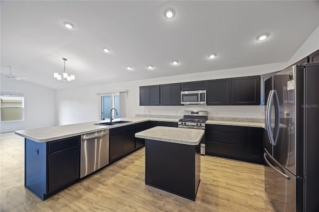 kitchen featuring sink, vaulted ceiling, appliances with stainless steel finishes, decorative light fixtures, and a kitchen island