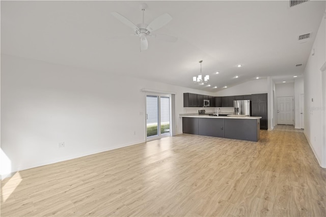 kitchen featuring ceiling fan with notable chandelier, sink, vaulted ceiling, light wood-type flooring, and stainless steel appliances