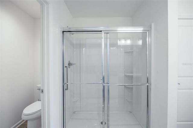 bathroom with a shower with door, wood-type flooring, and toilet