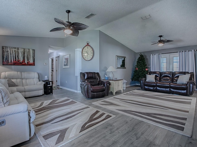 living room with lofted ceiling, a textured ceiling, and light wood-type flooring